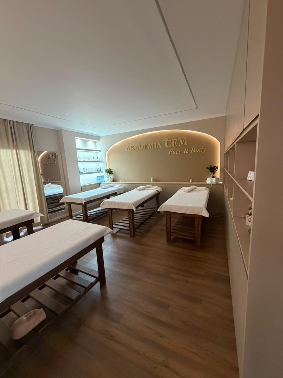 The Face and Body studio: five treatment beds with folded towels, product shelves and the lit arched wall.